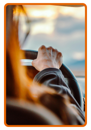 the arm and hand of a person holding onto a steering wheel.